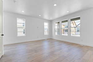 Empty room with light wood-style floors, recessed lighting, and a smoke detector