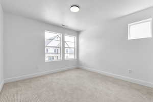Empty room featuring light colored carpet and a textured ceiling