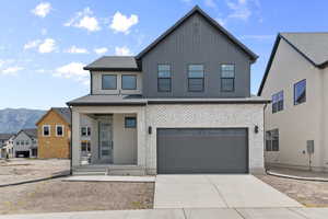 View of front facade featuring an attached garage, brick siding, a mountain view, and driveway