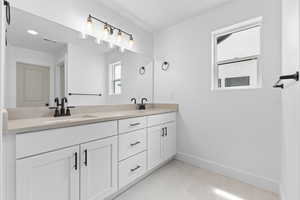 Full bath featuring double vanity and baseboards