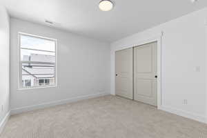 Unfurnished bedroom with light colored carpet and a closet