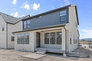 Rear view of house with a porch, a mountain view, and stucco siding