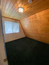 Additional living space featuring wood ceiling, carpet flooring, lofted ceiling, and wooden walls