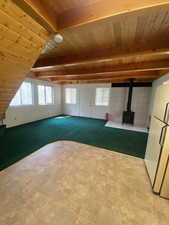 Unfurnished living room featuring a wood stove, wood ceiling, and light carpet