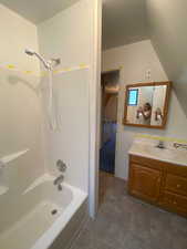 Bathroom featuring vanity, shower / tub combination, tile patterned flooring, and vaulted ceiling
