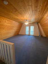 Bonus room with wooden ceiling, wooden walls, carpet flooring, a ceiling fan, and vaulted ceiling