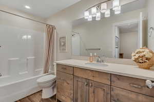 Bathroom with shower / bathtub combination with curtain, vanity, wood finished floors, and recessed lighting