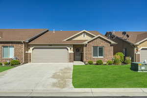 View of front of house featuring brick siding, a garage, a front yard, and concrete driveway