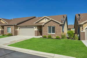 View of front of property with brick siding, driveway, a garage, a front lawn, and a shingled roof