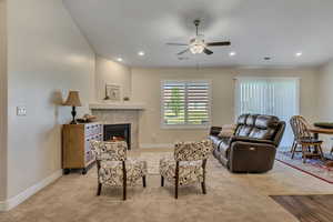 Living area with light carpet, a ceiling fan, a tile fireplace, and recessed lighting