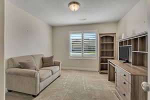 Office with a textured ceiling and light colored carpet