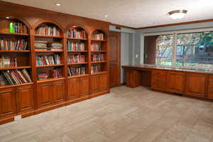 Library/office featuring crown molding, built in study area.