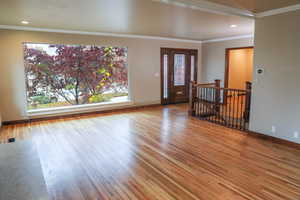 Entrance foyer featuring crown molding, beautiful hardwood flooring, along with oversized picture windows throughout.