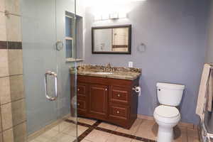 Bathroom featuring light tile patterned floors, vanity, a stall shower, and inlaid floor details