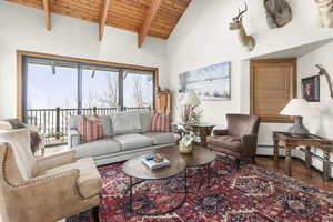 Living area featuring a wood ceiling with exposed beams, wood finished floors, and high vaulted ceiling