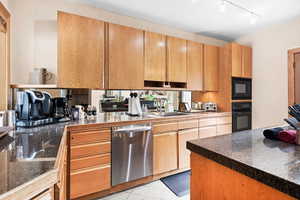 Kitchen with black appliances, track lighting, and light tile patterned flooring