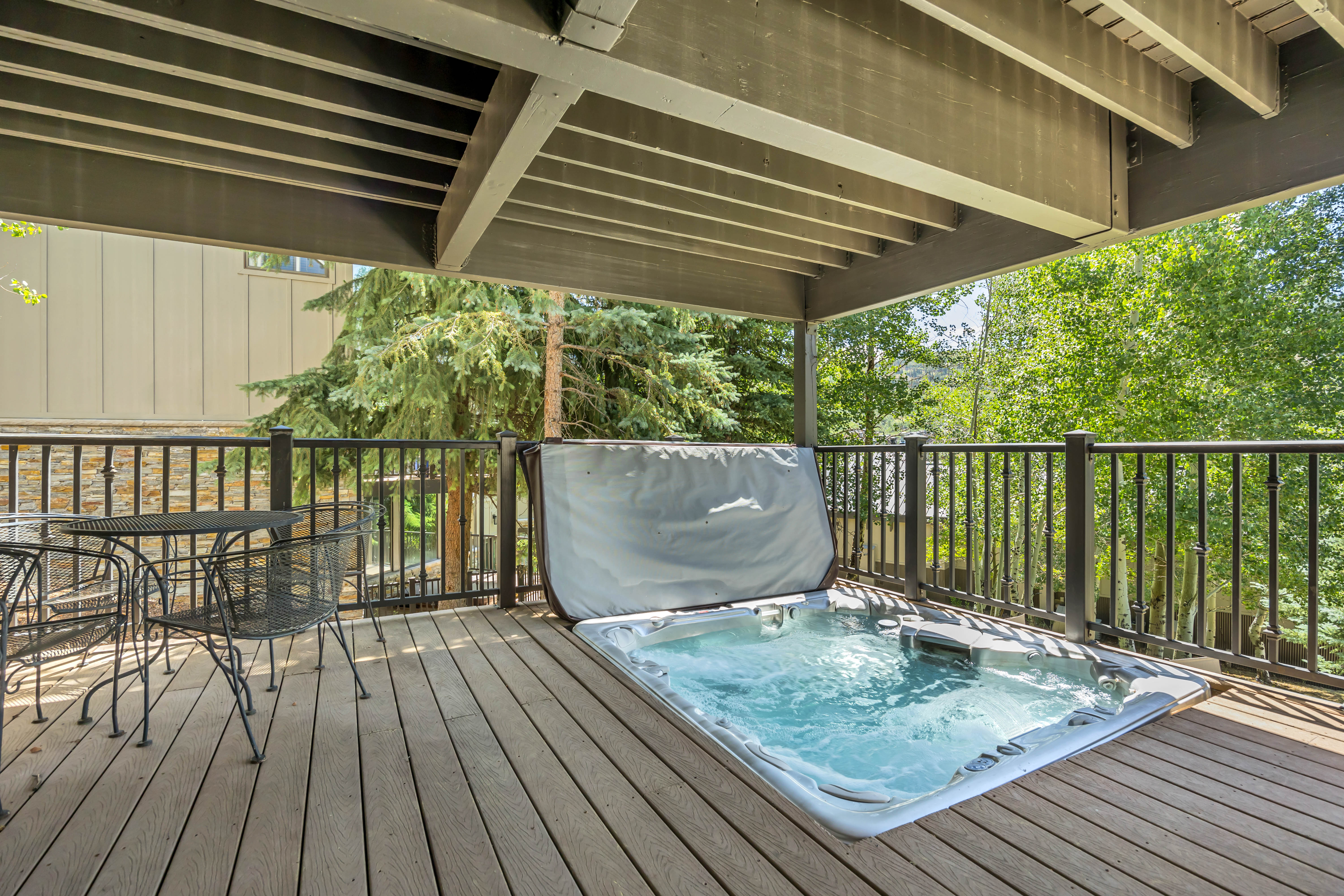 Wooden terrace with a covered hot tub and outdoor dining space
