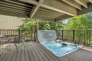 Wooden terrace with a covered hot tub and outdoor dining space
