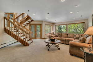 Carpeted living area featuring baseboard heating, stairway, recessed lighting, a textured ceiling, and french doors