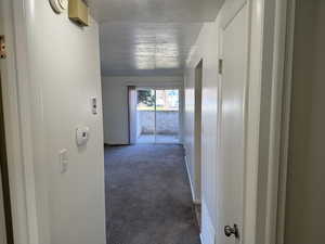 Hallway featuring dark colored carpet