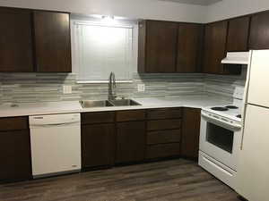 Kitchen featuring dark brown cabinets, white appliances, light countertops, dark wood-style floors, and range hood