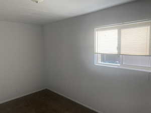 Unfurnished room with dark colored carpet and baseboards