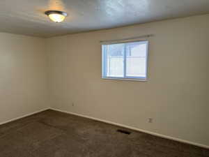Spare room with a textured ceiling and dark carpet