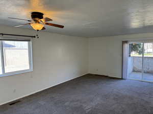 Carpeted empty room with a textured ceiling and ceiling fan
