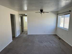 Carpeted spare room with ceiling fan and a textured ceiling