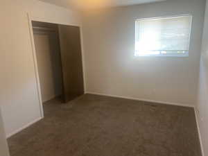 Unfurnished bedroom with dark colored carpet and a closet
