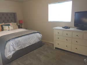 Bedroom featuring dark carpet and baseboards