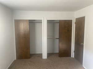 Unfurnished bedroom featuring multiple closets and light colored carpet