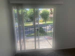 Doorway featuring carpet flooring and baseboards