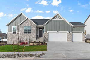 View of front of property featuring board and batten siding, a front lawn, driveway, and a garage