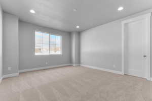 Empty room with light carpet and recessed lighting