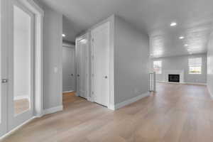 Unfurnished living room with light wood-style flooring, a glass covered fireplace, and recessed lighting
