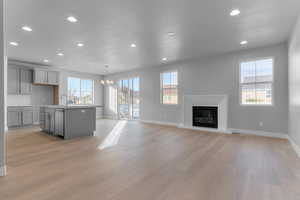 Kitchen with gray cabinets, a center island with sink, open floor plan, healthy amount of natural light, and recessed lighting