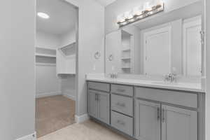 Full bathroom featuring a walk in closet, double vanity, light carpet, and light tile patterned floors