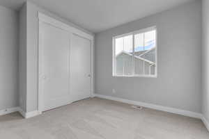 Unfurnished bedroom with light carpet and a closet