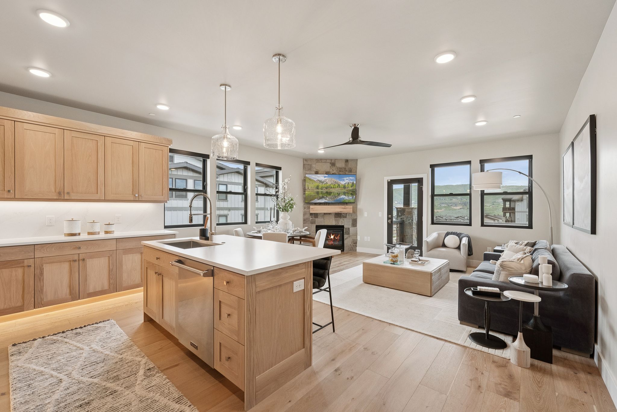 Kitchen featuring light brown cabinetry, dishwasher, a fireplace, light wood-style flooring, and light countertops