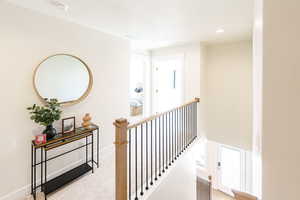 Hallway with an upstairs landing, carpet, and recessed lighting