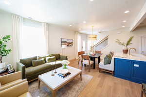 Living room with light wood-style flooring, stairway, and recessed lighting