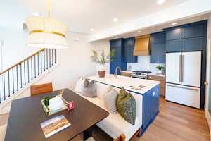 Kitchen featuring high end appliances, premium range hood, blue cabinets, light countertops, and recessed lighting