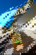 View of side of home featuring stucco siding, a garden, and a chimney