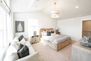 Bedroom with light colored carpet and lofted ceiling