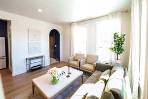 Living area with arched walkways, wood finished floors, and recessed lighting