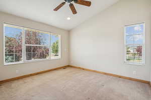 Carpeted empty room with lofted ceiling and a ceiling fan
