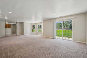 Unfurnished living room with plenty of natural light, carpet, a textured ceiling, and recessed lighting