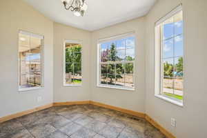 Empty room featuring a chandelier and dark stone finish floors