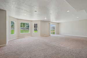 Unfurnished room with carpet flooring, a textured ceiling, recessed lighting, and healthy amount of natural light